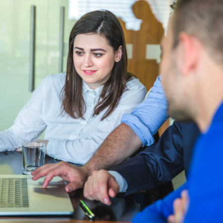 Jóvenes y mentores colaborando frente a un portátil en un entorno de innovación.