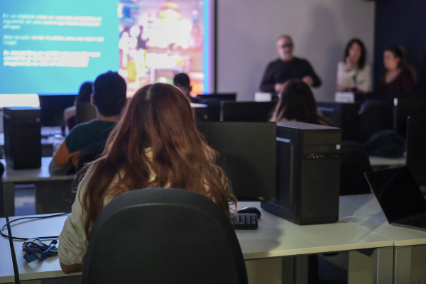 Aula con jóvenes frente a ordenadores mientras una persona imparte formación sobre habilidades TIC dentro del programa IT Skills.