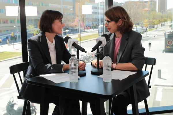 Dos mujeres conversan en una mesa con micrófonos y botellas de agua, grabando un podcast sobre tecnología, liderazgo y el entorno empresarial desde la perspectiva femenina.